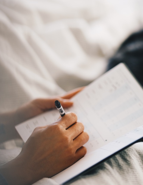 Woman filling out her Kick sleep journal in bed right after
              waking up